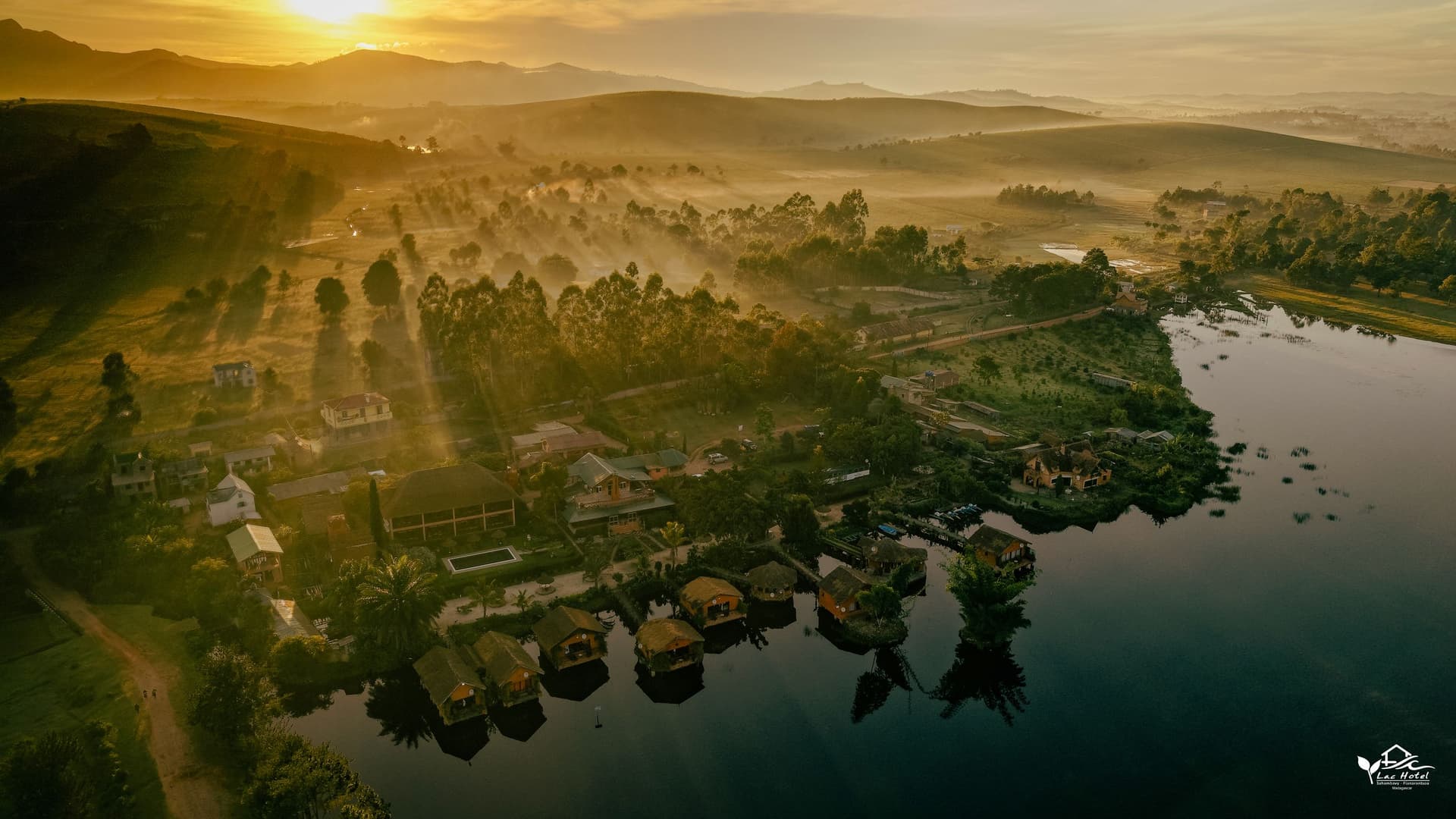 Sunrise over Lac Hôtel Sahambavy, the overwater bungalows and the hills, seen from the air