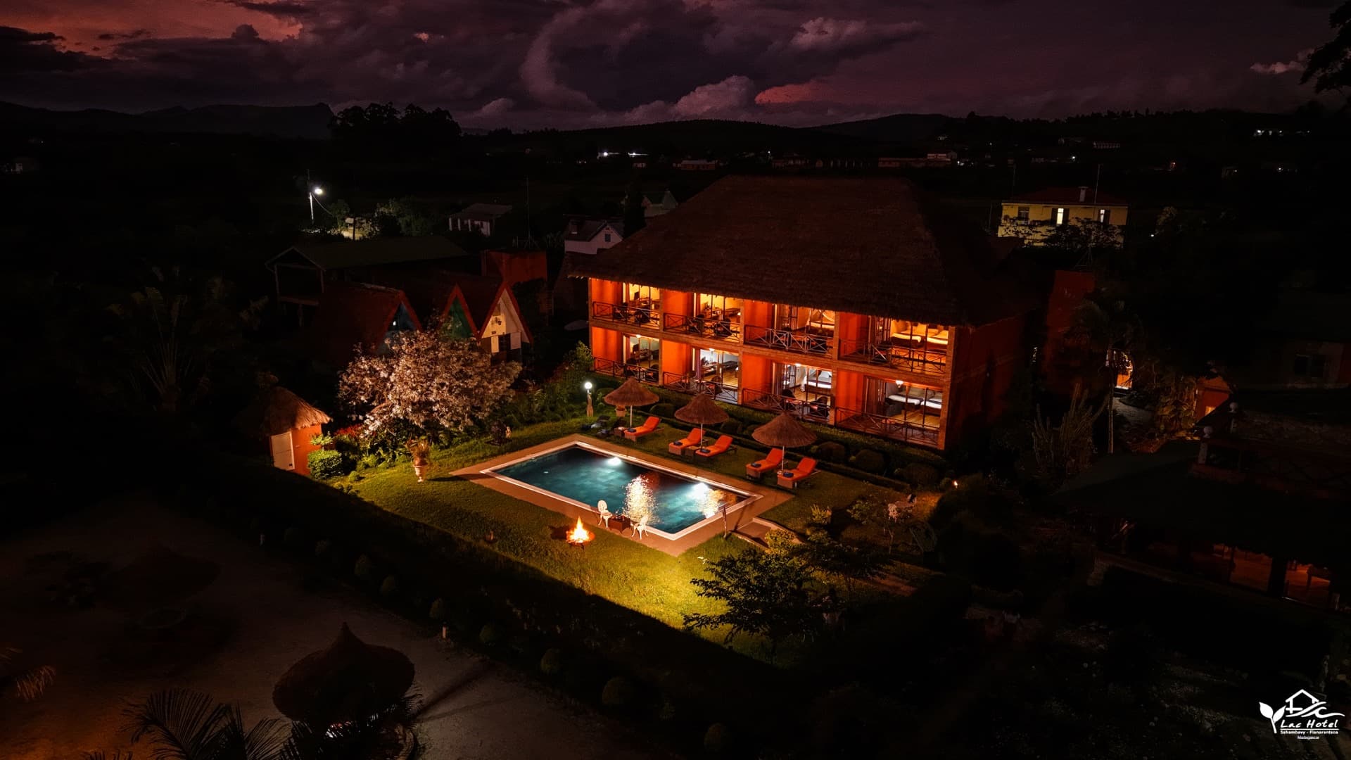 Le Lac Hôtel illuminé à la nuit tombée, piscine et brasero dans les jardins