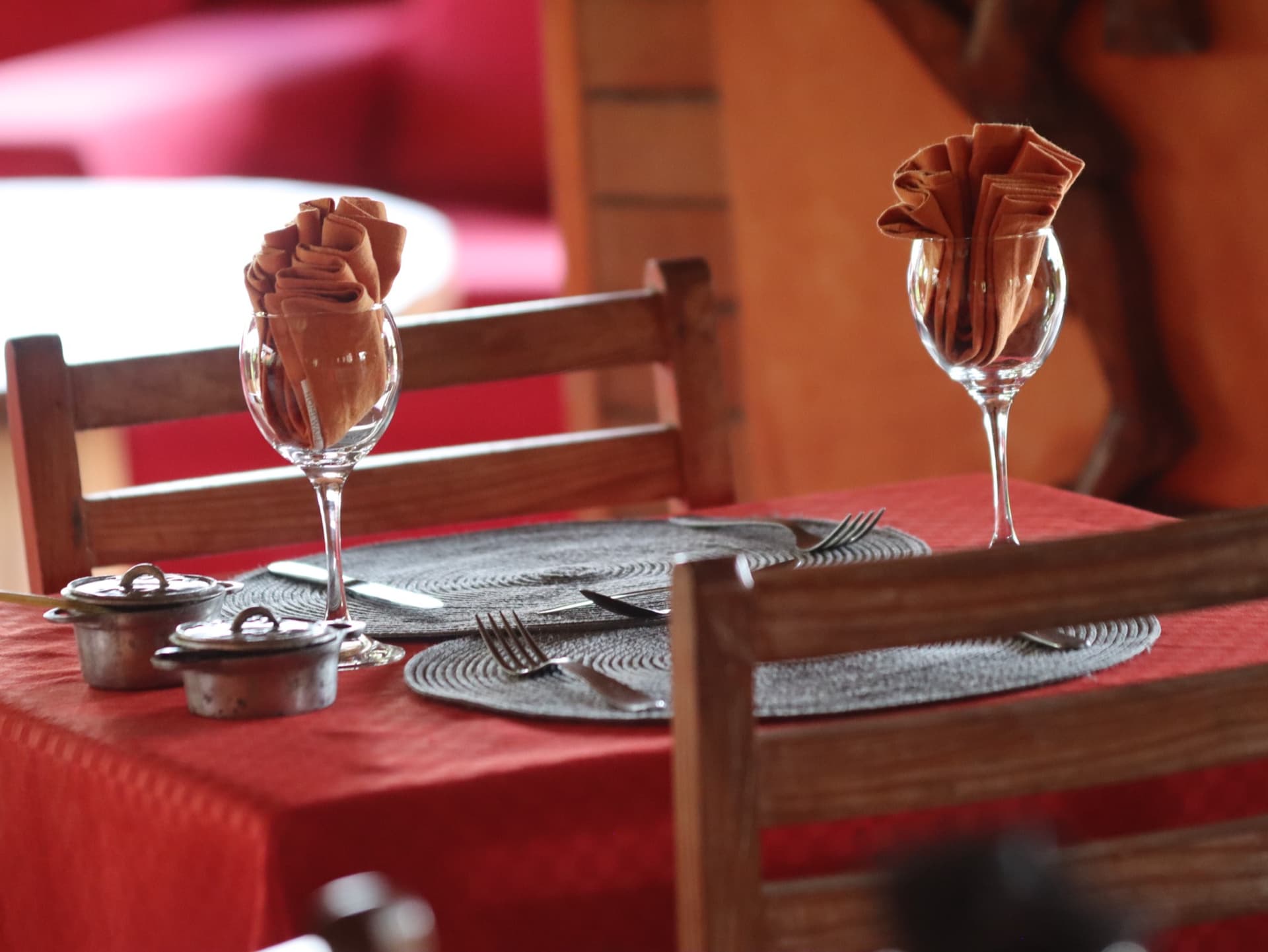 Table laid with a red cloth, napkins folded into the wine glasses