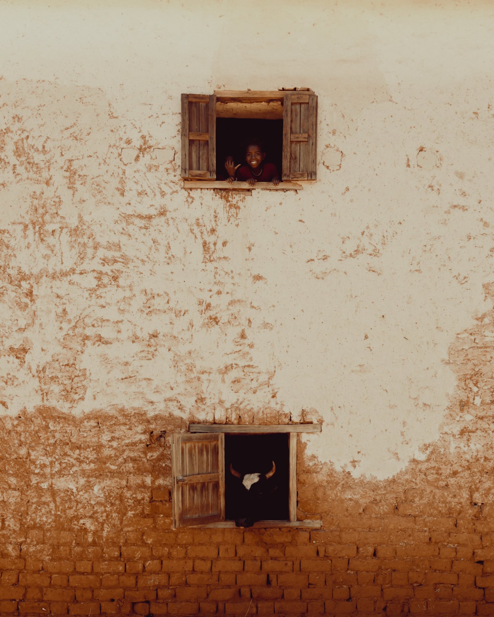 Maison betsileo traditionnelle avec des enfants aux fenêtres
